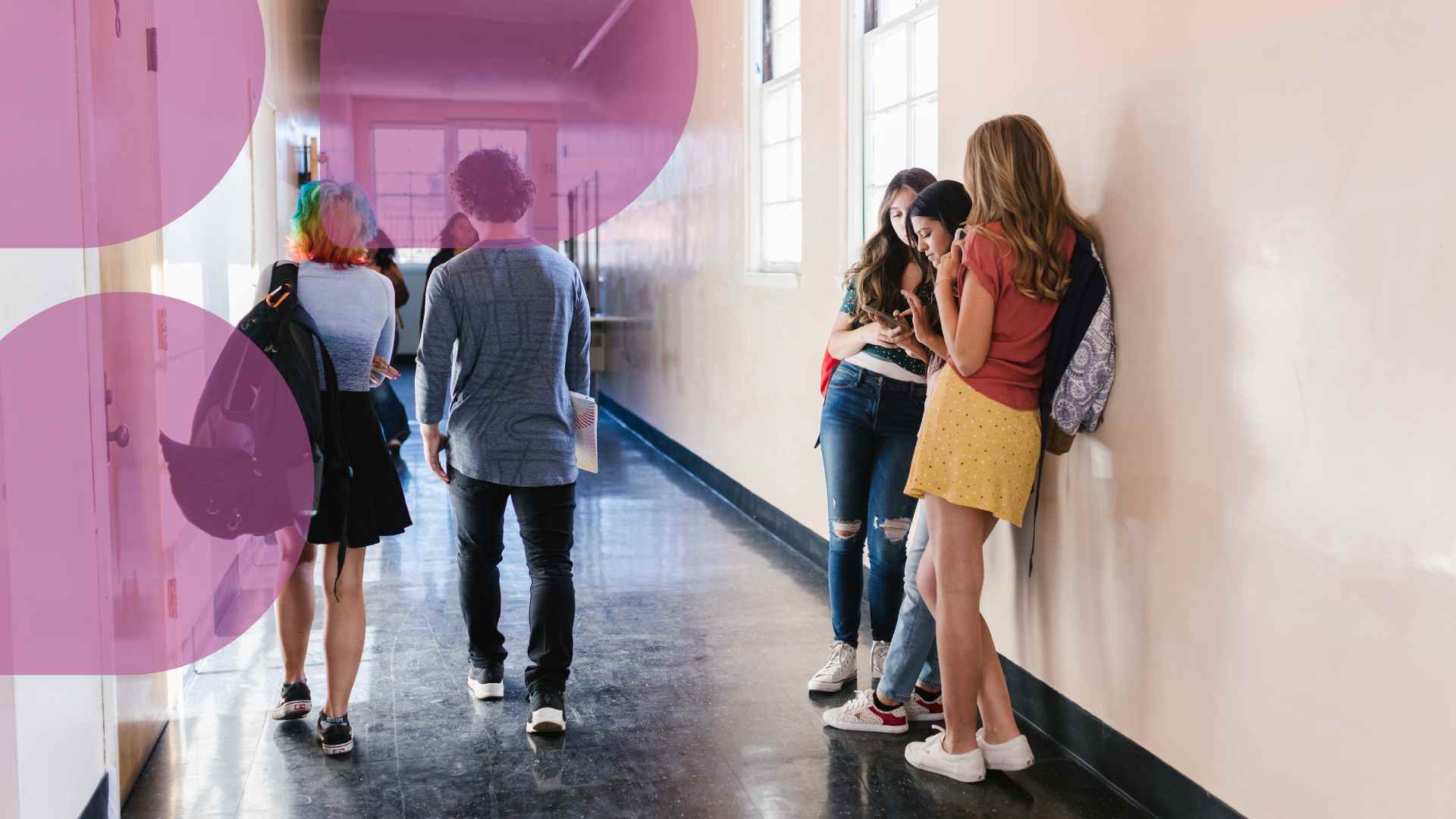 Koulun käytävällä kaksi oppilasta nojaa seinään ja tutkivat puhelinta. Kaksi oppilasta kävelee selkä katsojaan päin käytävää eteenpäin. Yläreunassa pinkkejä pisaran muotoisia kuvaelementtejä.