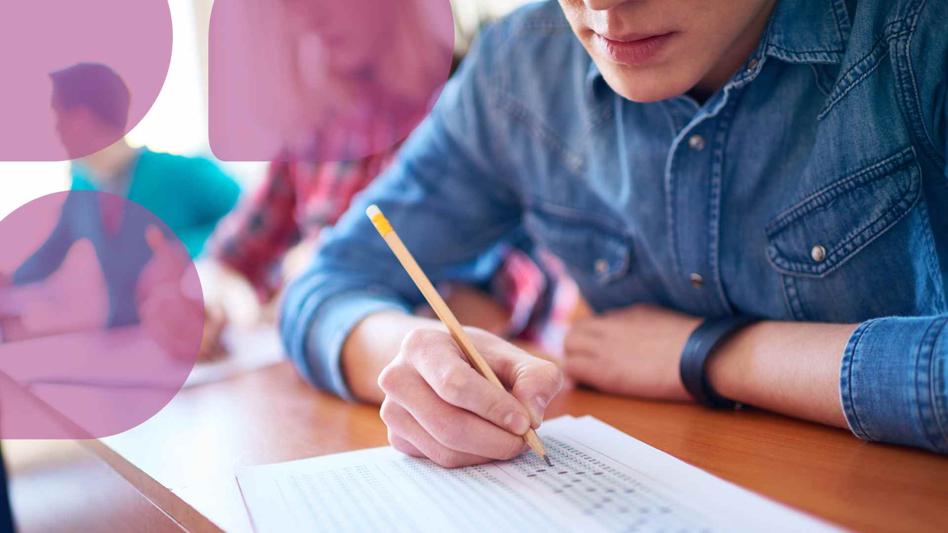 Oppilas istuu pöyrän ääressä ja kirjoittaa kynälä paperille. Yläreunassa pinkkejä pisaran muotoisia kuvaelementtejä.